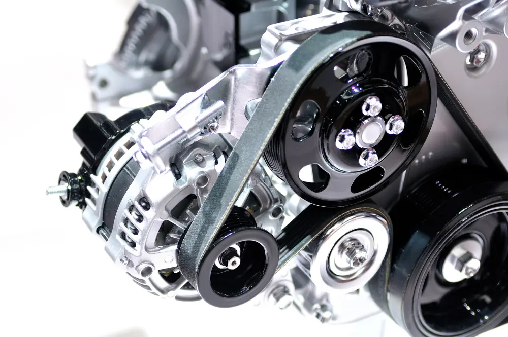 Close-up of a car engine's serpentine belt system with black pulleys, alternator, and polished aluminum components